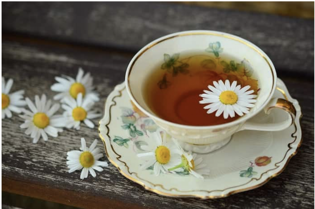 Cup of chamomile tea in flowered tea cup and saucer